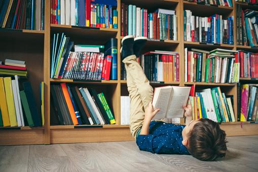 World Book Day.  A small child reading a book on the floor in a library